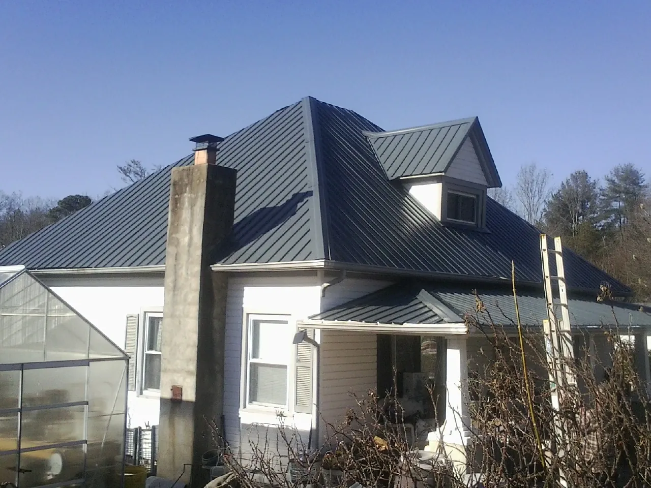 Dark blue standing seam metal roof on a white farmhouse with dormer — Slate & Tile Roof Repair by Roofing Brothers in Jbsa Ft Sam Houston