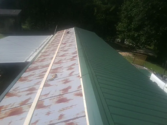 Old rusted panels beside newly installed green metal roofing — Wind Damage Roof Repair by Roofing Brothers in Jbsa Ft Sam Houston