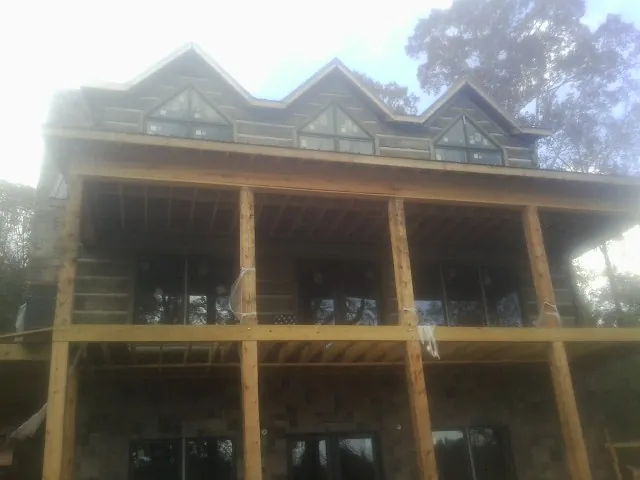 Dormers and porch framing on a large log home under construction — Roof Coating work by our crew in Jbsa Ft Sam Houston