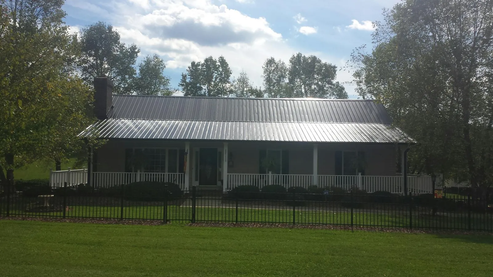 Gray metal roof on a brick ranch with a full width front porch — Gutter Guard Installation work by our crew in Jbsa Ft Sam Houston