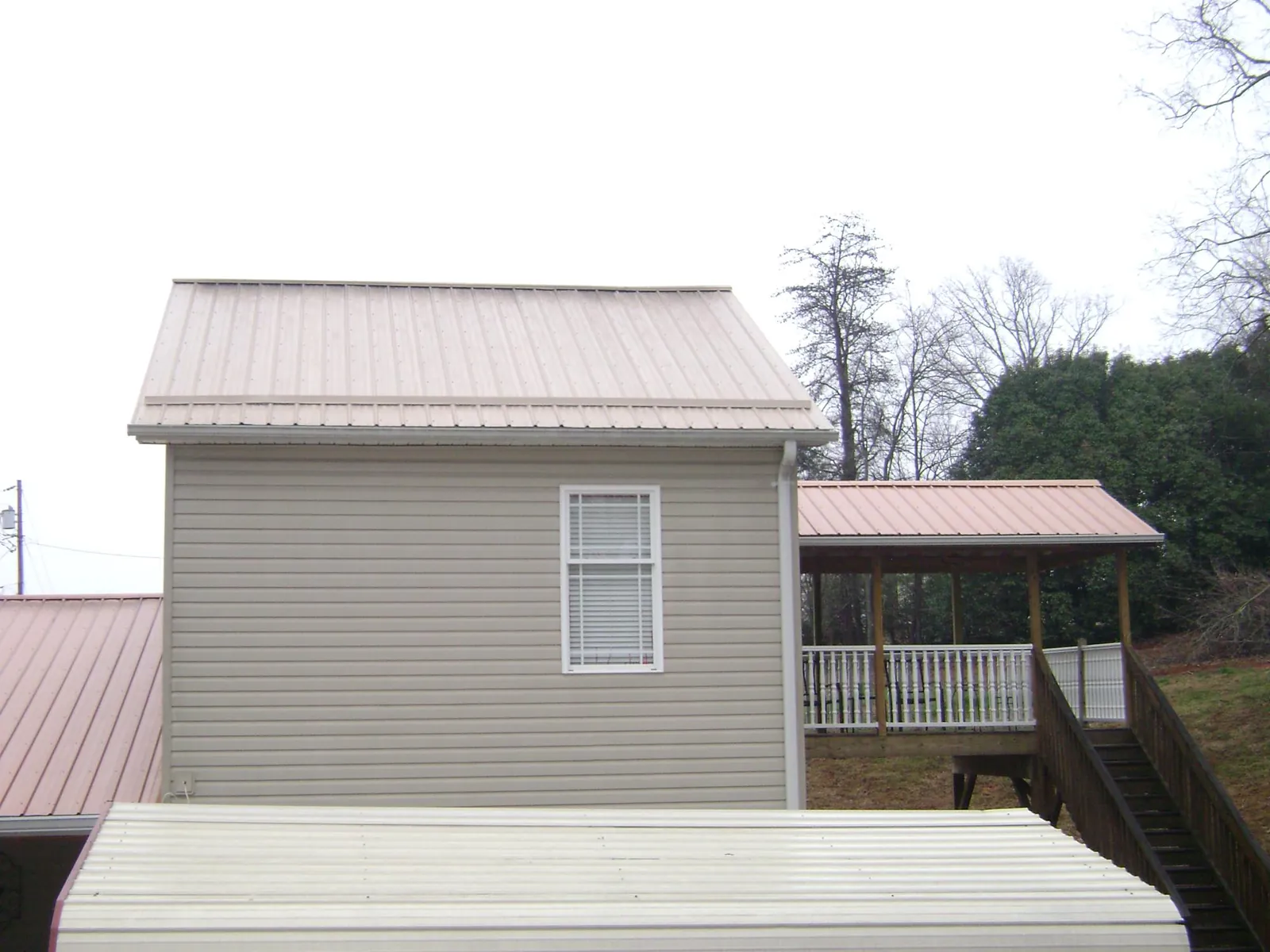 Tan metal roofs on a two story addition and attached porch, from a Roof Replacement job in Jbsa Ft Sam Houston